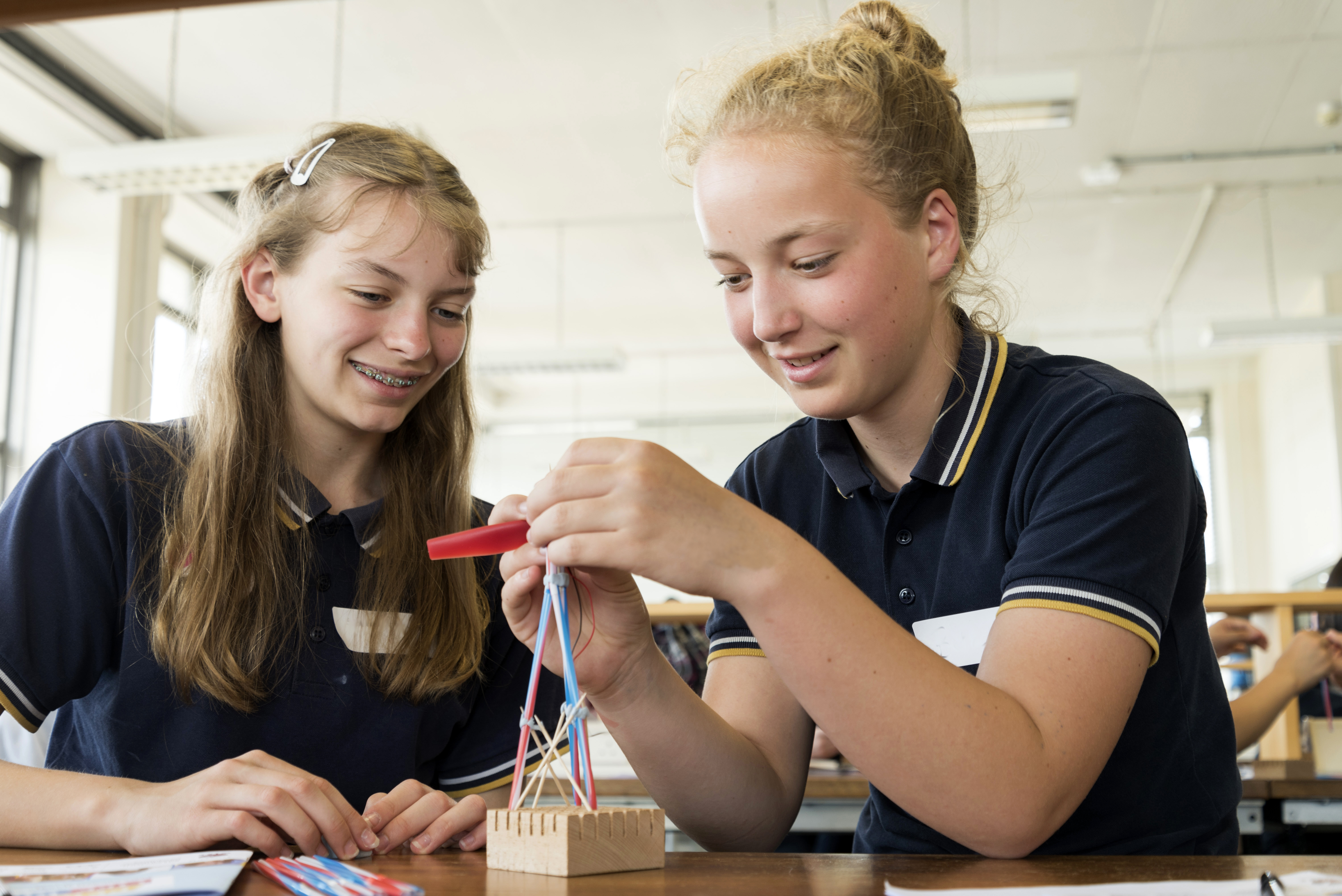 Two girls building a small tower shape project.